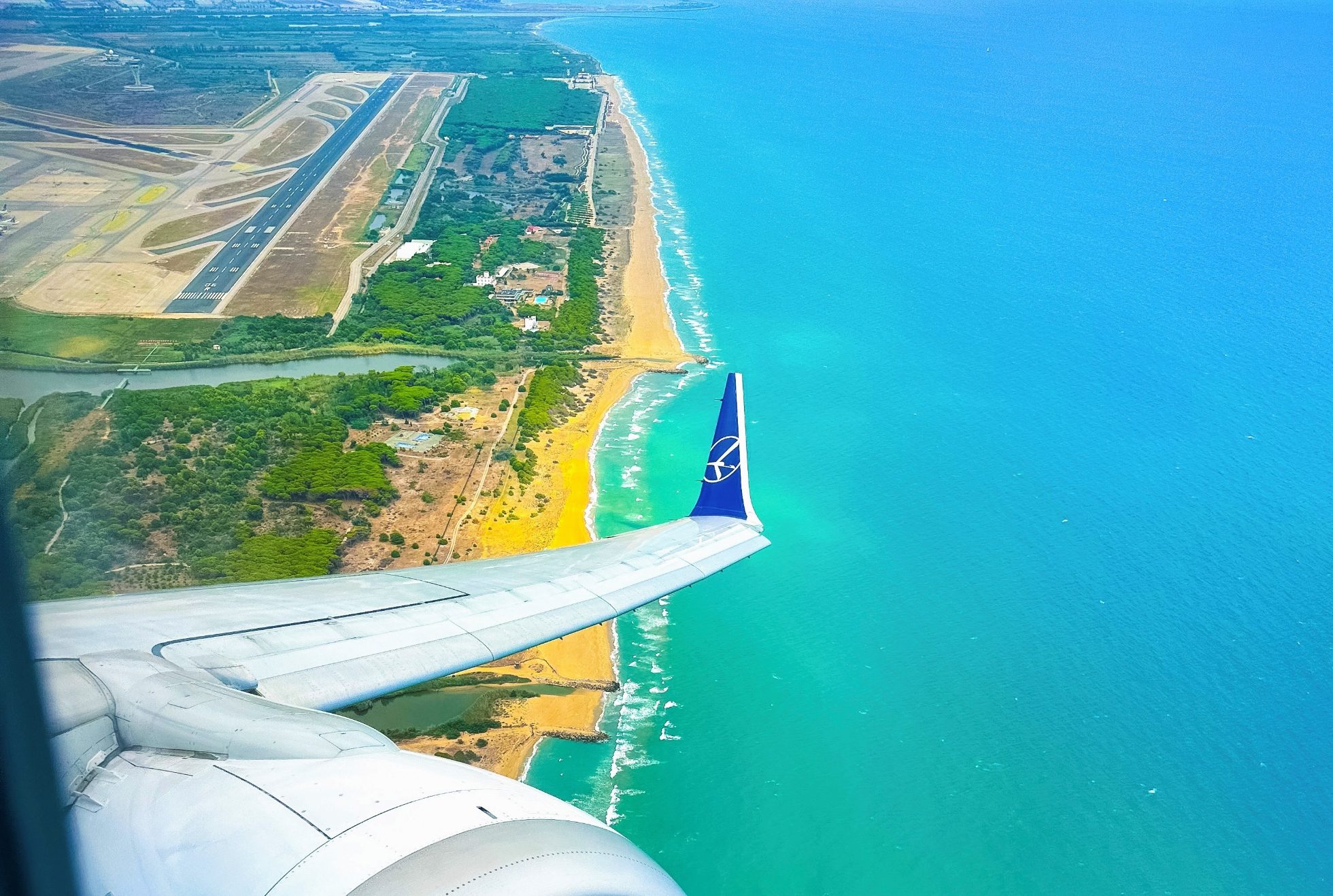 skrzydło Boeinga 737 MAX po starcie z Barcelony z widokiem na morze, wybrzeże i pas startowy
